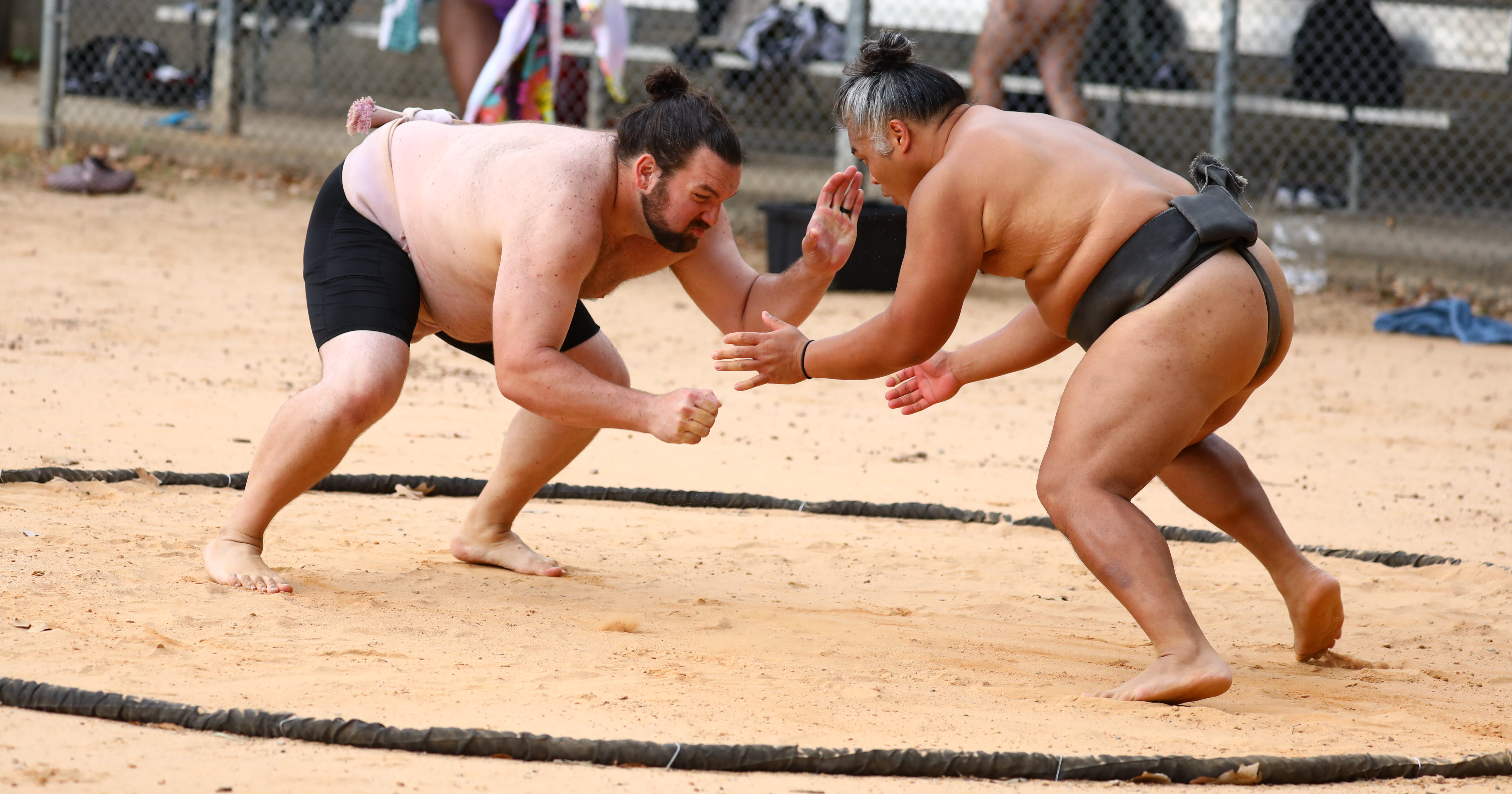 Two sumo wrestlers engaged in a bout on the sand ring